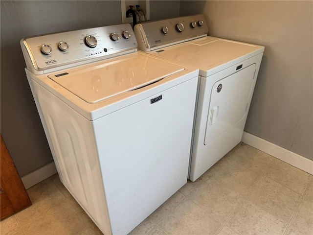 clothes washing area featuring laundry area, baseboards, washing machine and clothes dryer, and light tile patterned flooring