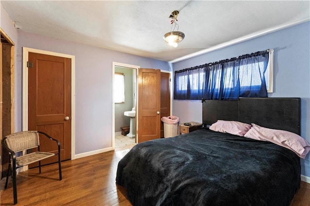 bedroom featuring connected bathroom, baseboards, and wood finished floors