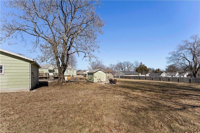 view of yard featuring fence, a storage unit, and an outbuilding