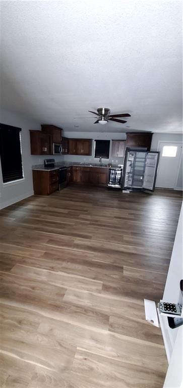 interior space with a ceiling fan, a textured ceiling, and wood finished floors