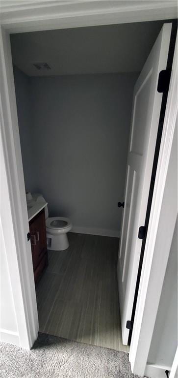 bathroom featuring visible vents, toilet, vanity, wood finished floors, and baseboards