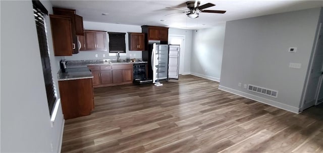 kitchen with dark wood-style flooring, visible vents, stove, a ceiling fan, and baseboards