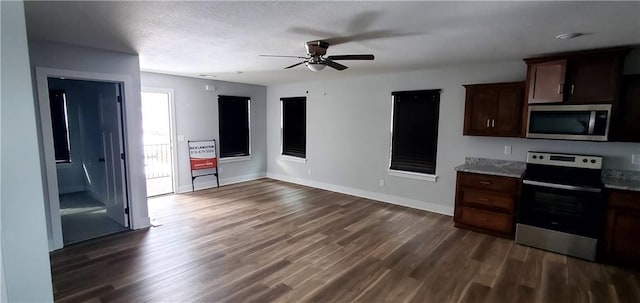 kitchen with light stone counters, dark wood-type flooring, baseboards, dark brown cabinets, and appliances with stainless steel finishes