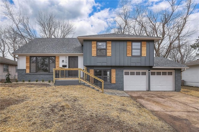 split level home with concrete driveway, roof with shingles, an attached garage, board and batten siding, and brick siding