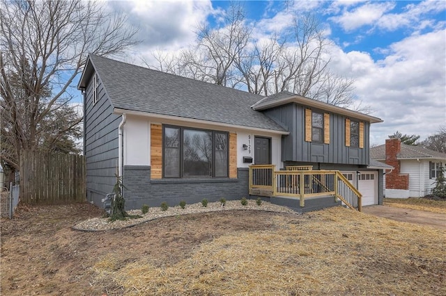 split level home with a garage, a shingled roof, fence, concrete driveway, and board and batten siding