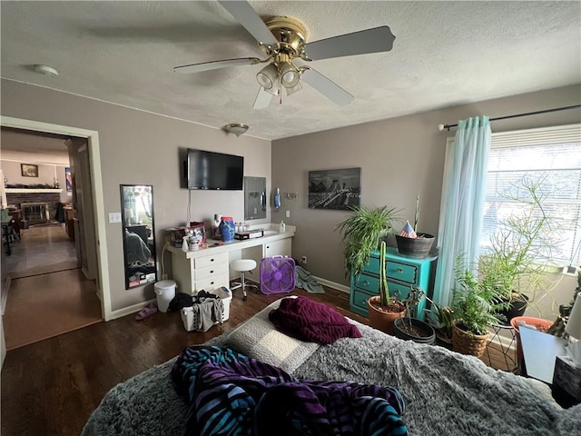 bedroom with dark wood-style floors, ceiling fan, a textured ceiling, and baseboards