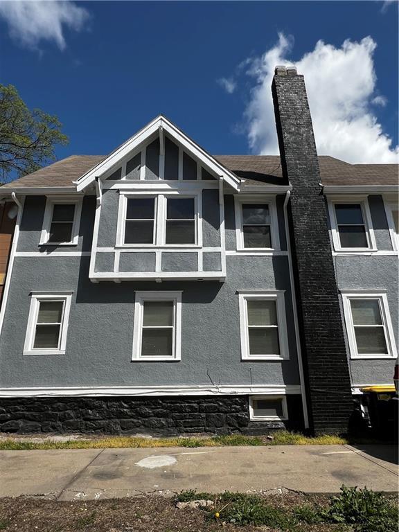 view of side of property featuring a shingled roof, a chimney, and stucco siding