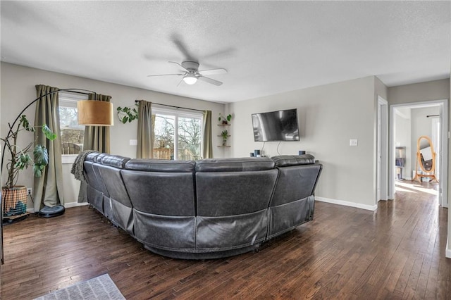 living area with dark wood-type flooring, plenty of natural light, baseboards, and a textured ceiling