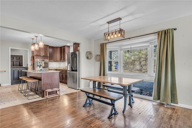 dining space with light wood-style flooring and baseboards