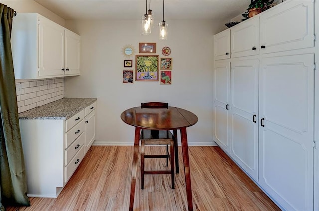 kitchen featuring baseboards, decorative backsplash, white cabinetry, and light wood-style floors