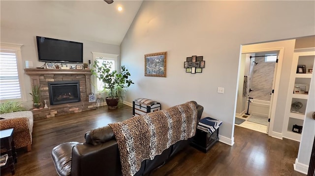 living area featuring high vaulted ceiling, baseboards, dark wood-style flooring, and a stone fireplace