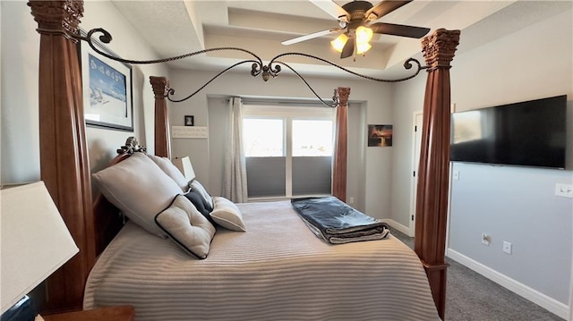 bedroom with carpet floors, access to outside, a tray ceiling, and baseboards