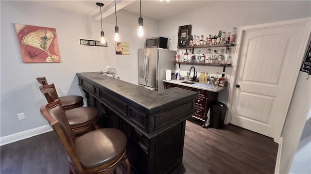 bar featuring wet bar, decorative light fixtures, dark wood finished floors, and stainless steel fridge with ice dispenser