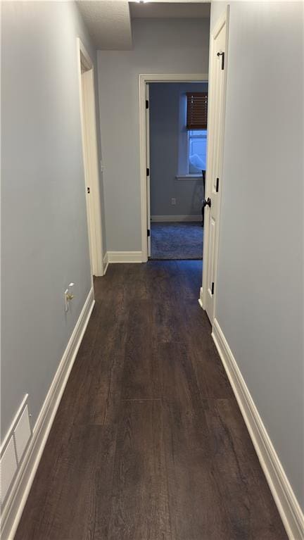 corridor with visible vents, dark wood finished floors, and baseboards