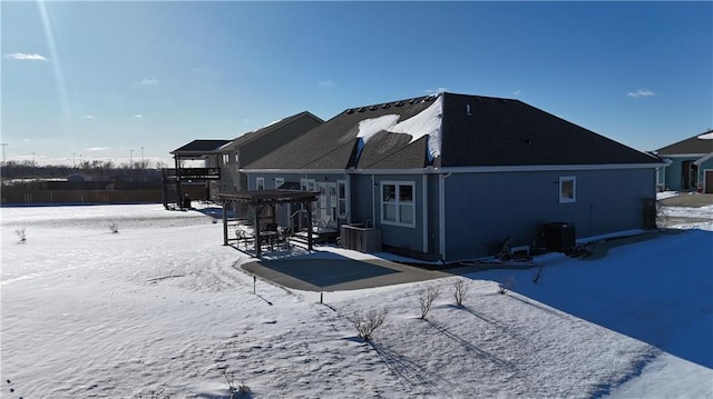 snow covered property featuring central AC unit and a pergola