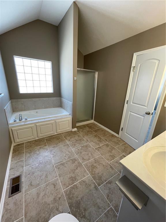 bathroom with a garden tub, visible vents, a stall shower, vaulted ceiling, and vanity