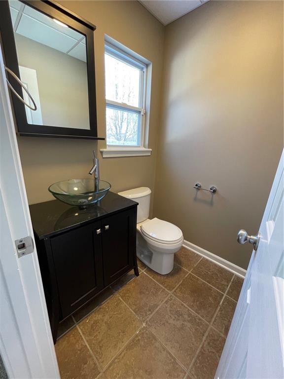 half bathroom featuring toilet, vanity, and baseboards