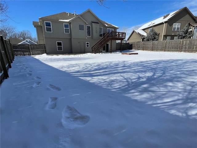 yard covered in snow with fence private yard, stairway, and a wooden deck