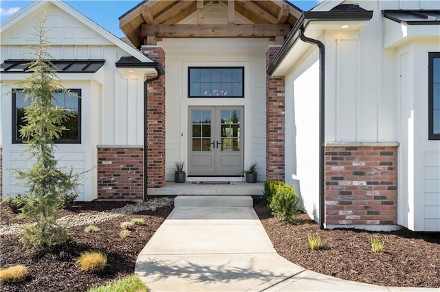 view of exterior entry with french doors, board and batten siding, and brick siding