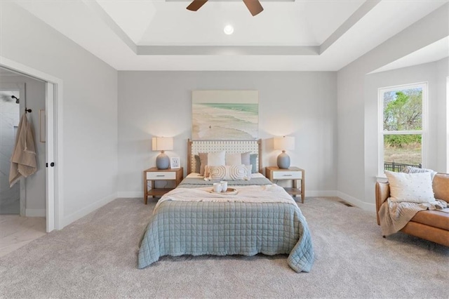 carpeted bedroom featuring ceiling fan, a tray ceiling, and baseboards