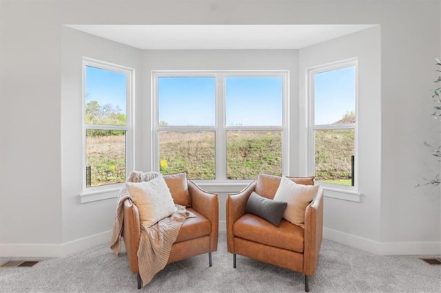 living area with visible vents, light colored carpet, and baseboards