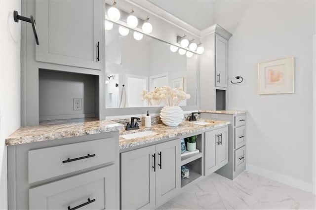 bathroom with baseboards, marble finish floor, double vanity, and a sink