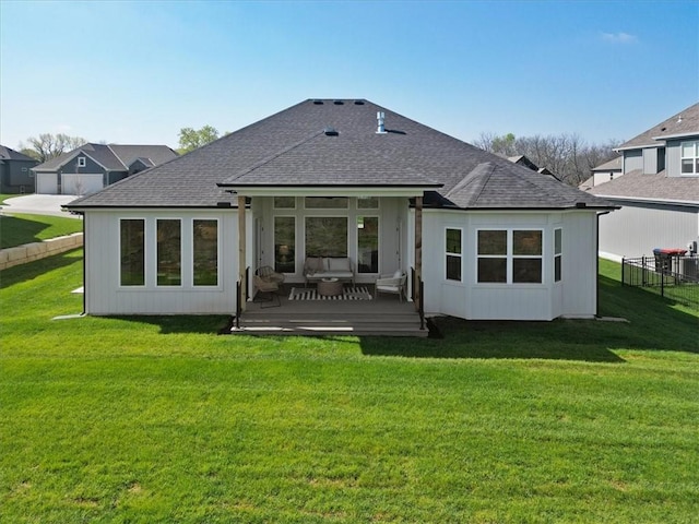 back of house with a lawn, a wooden deck, fence, and roof with shingles