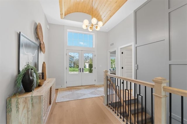 foyer entrance featuring a chandelier, visible vents, light wood-style flooring, baseboards, and wood ceiling