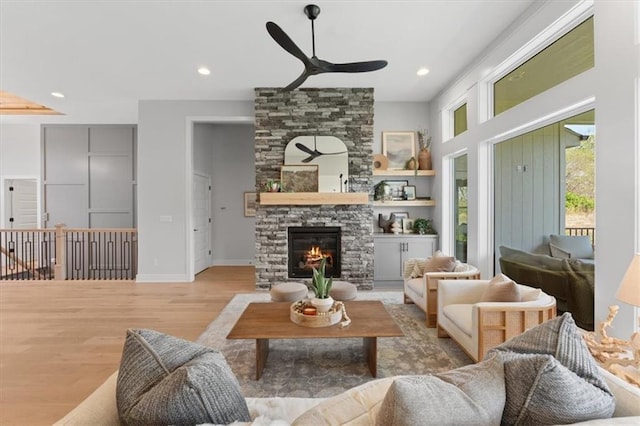 living room featuring a stone fireplace, wood finished floors, a ceiling fan, and recessed lighting
