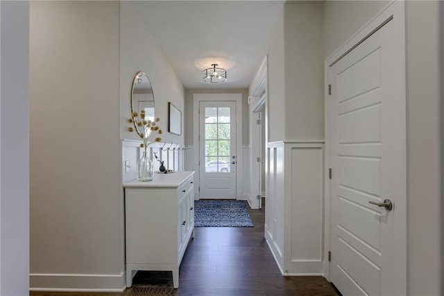 entryway featuring dark wood-style flooring, wainscoting, and a decorative wall