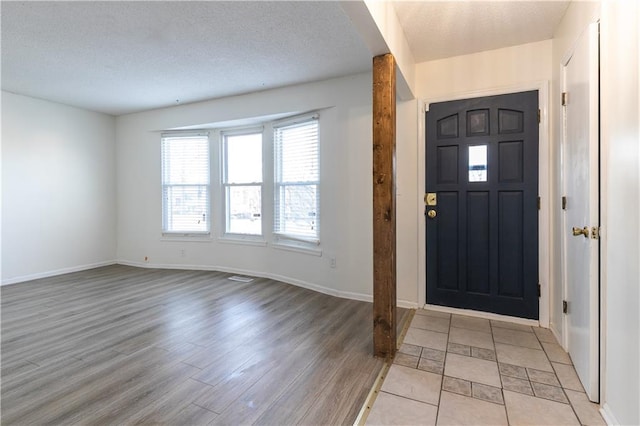 entryway featuring light wood-type flooring, baseboards, and a textured ceiling