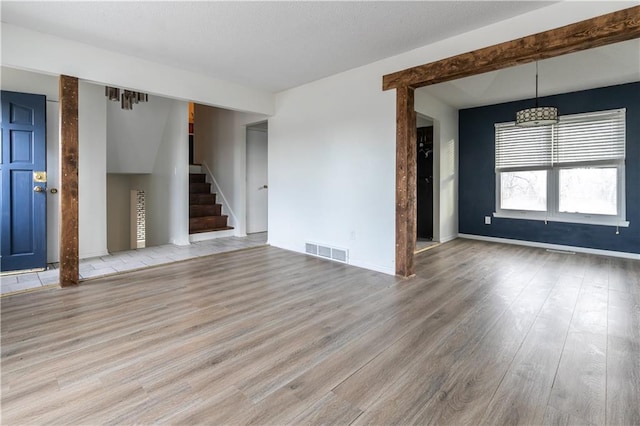 interior space with stairs, wood finished floors, visible vents, and baseboards