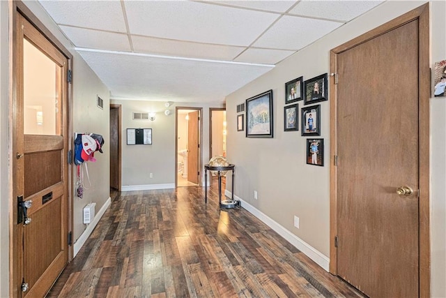 hallway featuring a paneled ceiling, baseboards, and dark wood-style flooring