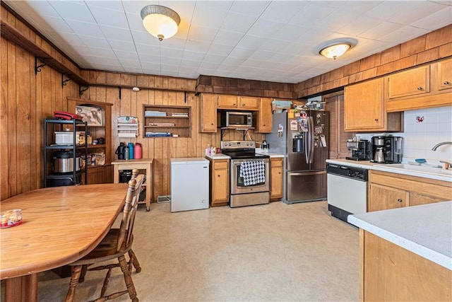 kitchen featuring brown cabinets, light floors, light countertops, appliances with stainless steel finishes, and a sink