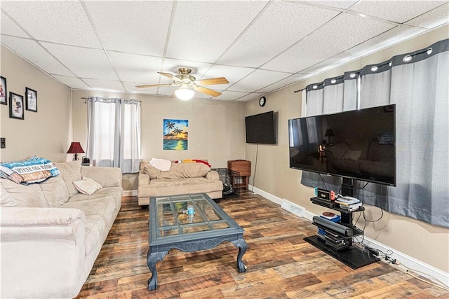 living area featuring dark wood-style floors, a ceiling fan, and a drop ceiling