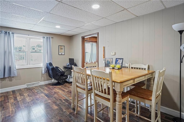 dining room featuring baseboards, visible vents, dark wood finished floors, and a drop ceiling