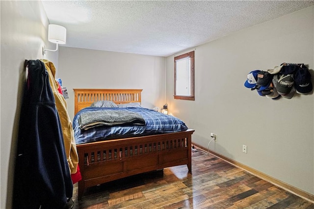 bedroom with dark wood-style floors, a textured ceiling, and baseboards