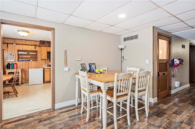 dining space featuring a paneled ceiling, dark wood-style flooring, visible vents, and baseboards