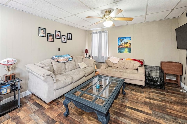 living area featuring dark wood-style floors, ceiling fan, baseboards, and a drop ceiling