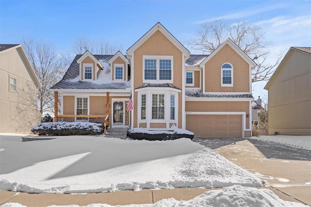 traditional home with an attached garage, covered porch, driveway, and stucco siding