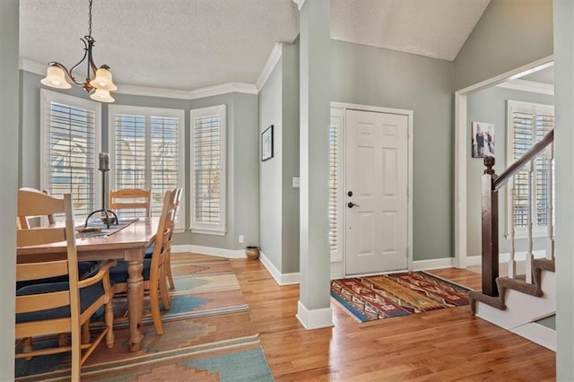 entrance foyer featuring stairs, crown molding, wood finished floors, and a notable chandelier