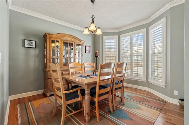 dining room with a chandelier, wood finished floors, a wealth of natural light, and baseboards