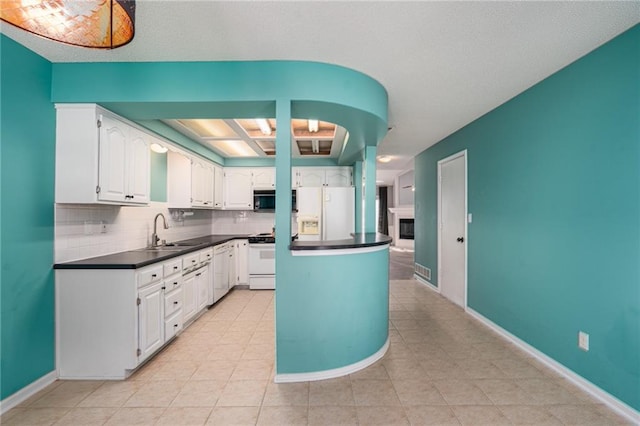 kitchen featuring dark countertops, decorative backsplash, white cabinetry, a sink, and white appliances