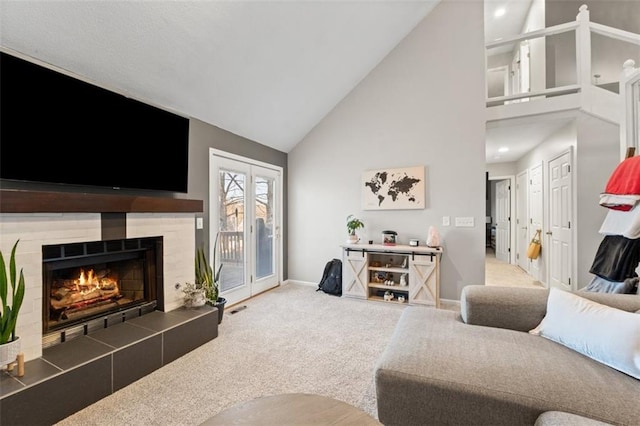 living area with visible vents, baseboards, a tiled fireplace, carpet flooring, and high vaulted ceiling