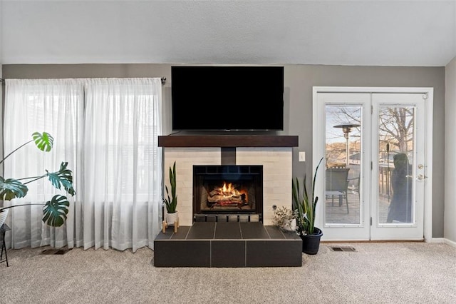 living area with visible vents, plenty of natural light, carpet, and a fireplace