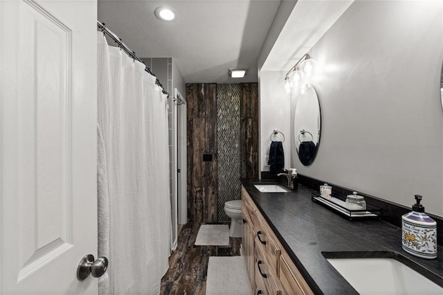 full bathroom featuring a sink, toilet, wood finished floors, and double vanity