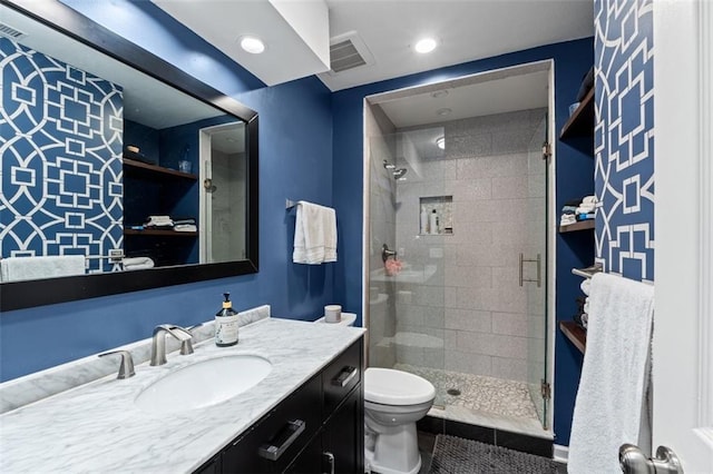 bathroom featuring visible vents, a shower stall, toilet, and vanity