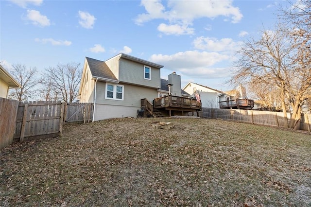 rear view of house with a fenced backyard and a deck