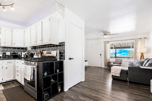 kitchen featuring dark countertops, stainless steel gas range oven, white cabinets, and open floor plan