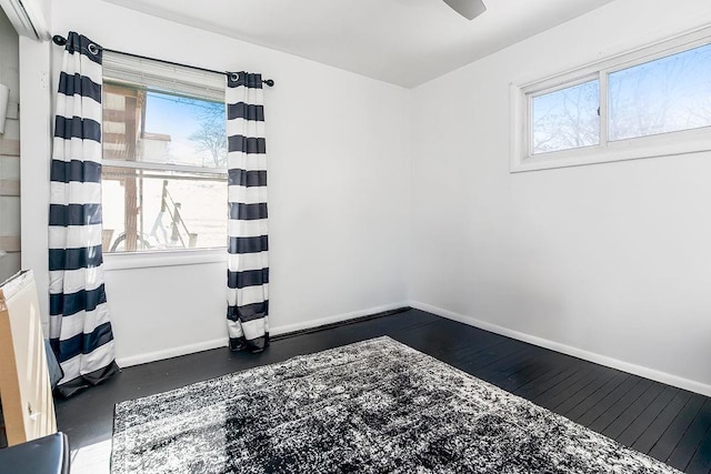 empty room featuring baseboards and dark wood-type flooring